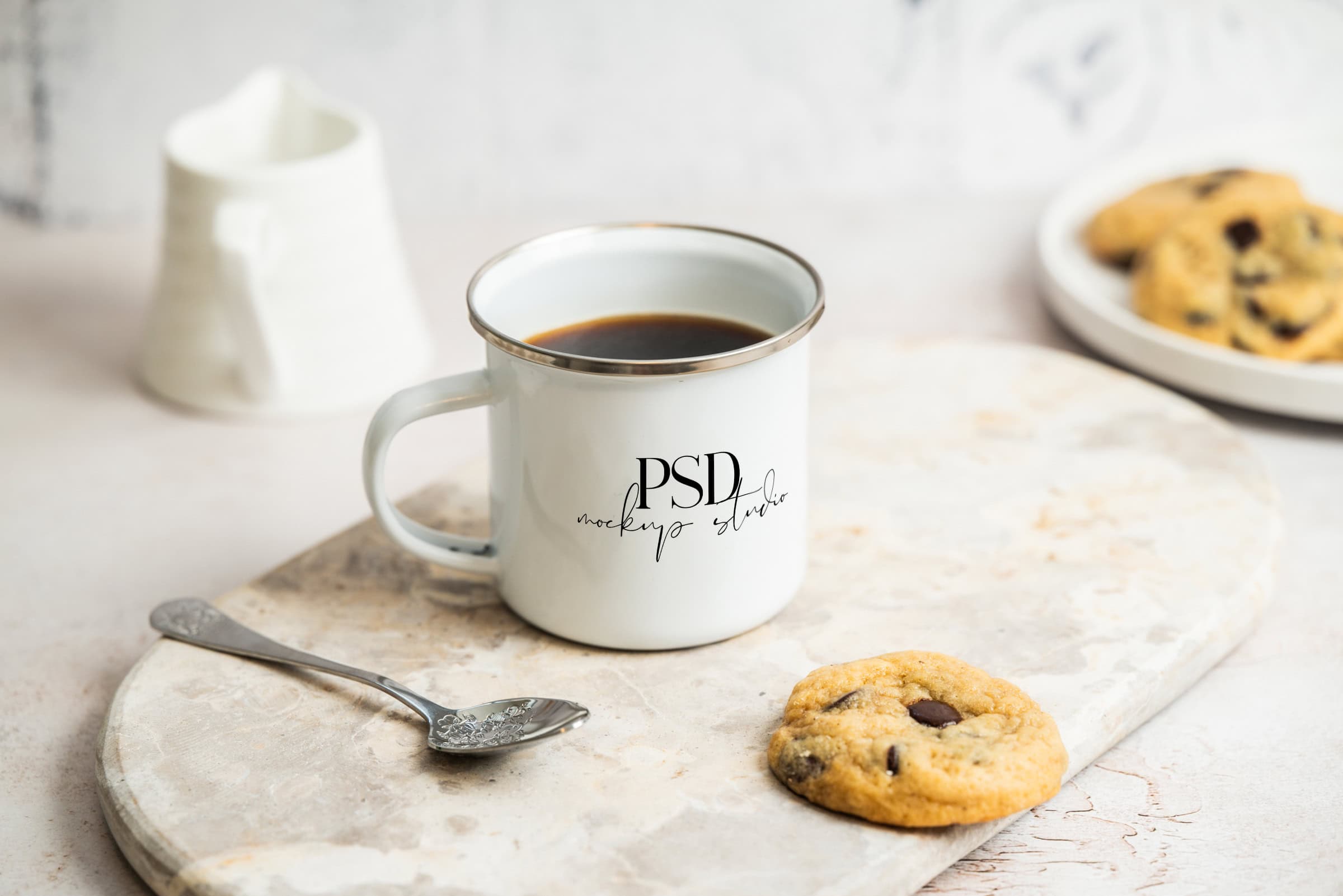 A Soft Light Kitchen Mug Mockup | White 11oz | PSD (Copy) sits on a light surface filled with coffee, accompanied by a chocolate chip cookie and spoon, with a small pitcher and plate of cookies in the background.