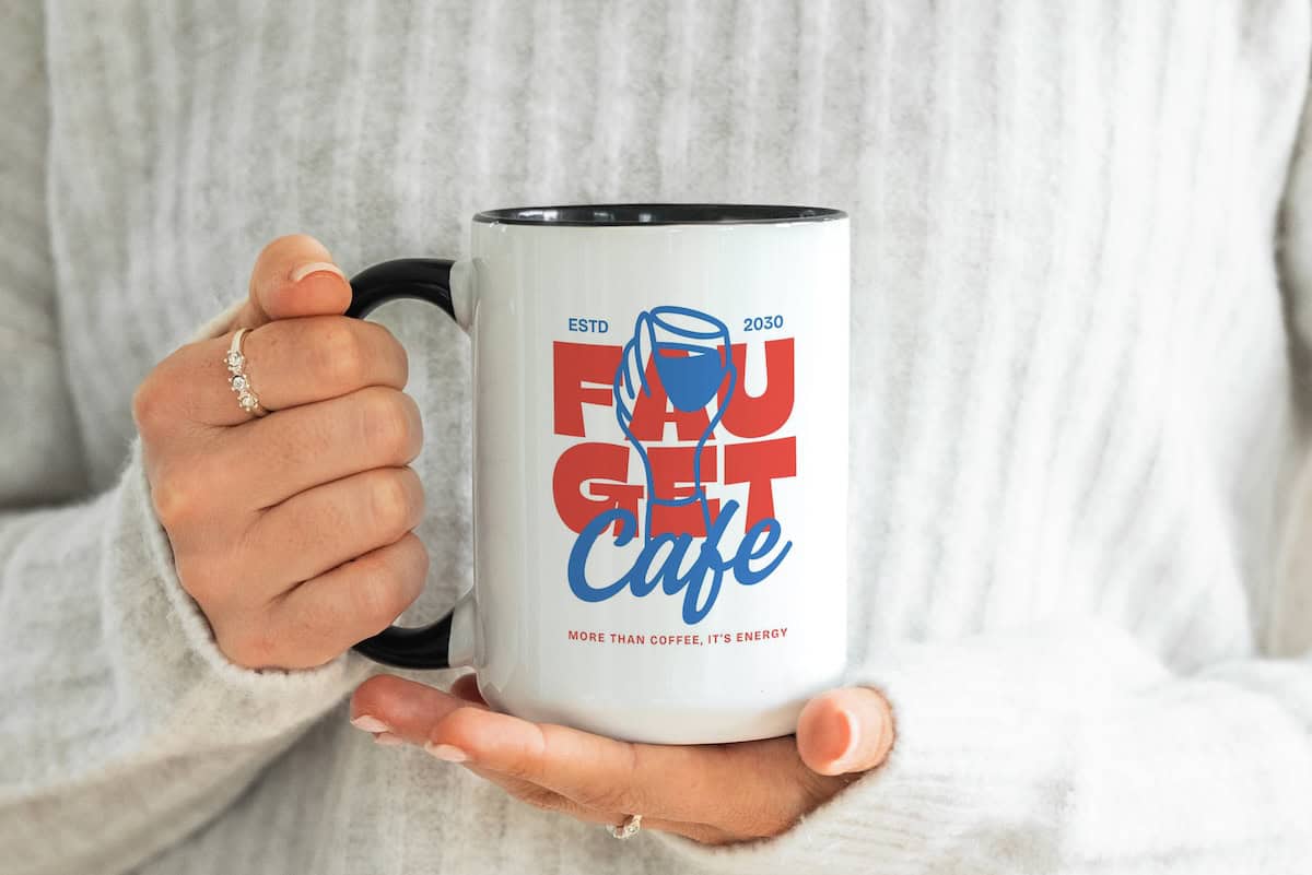 A person in a white sweater holds a white mug with black rim. The mug reads Faucet Café in bold letters with a blue faucet graphic and the tagline More than coffee, its energy!.